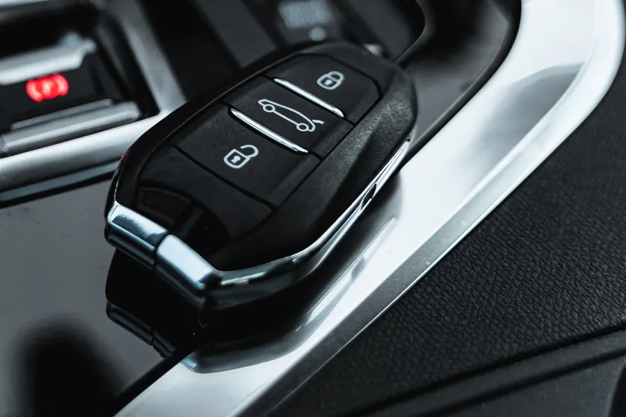 Remote starter fob in hand with a white sedan parked in the snow
